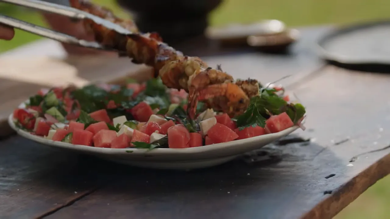 Golden bacon-wrapped prawn skewers ready to serve with watermelon feta salad