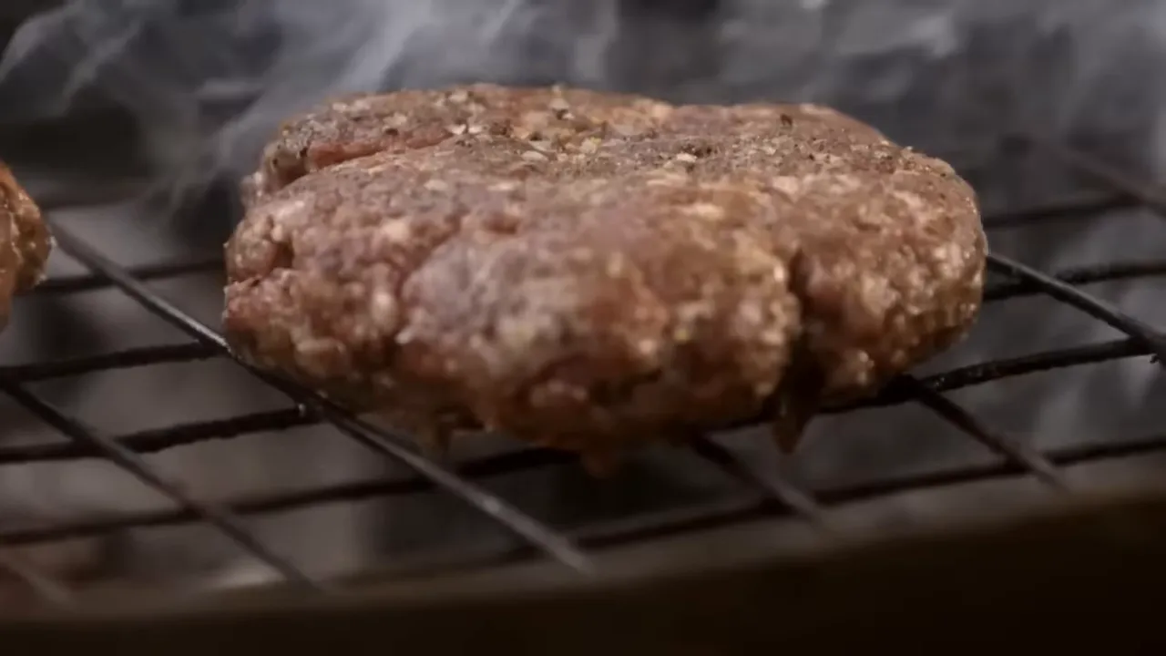 Beef burger searing on the grill with fat sizzling and smoke kissing the meat