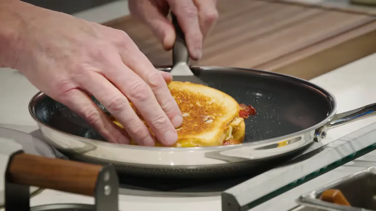 Golden grilled cheese sandwich being pressed with a spatula in a skillet