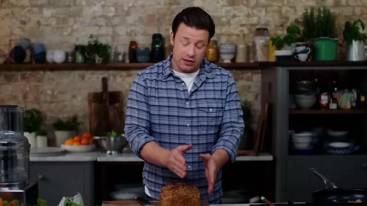 presenter showing a seeded brown loaf on a board, ready for croutons