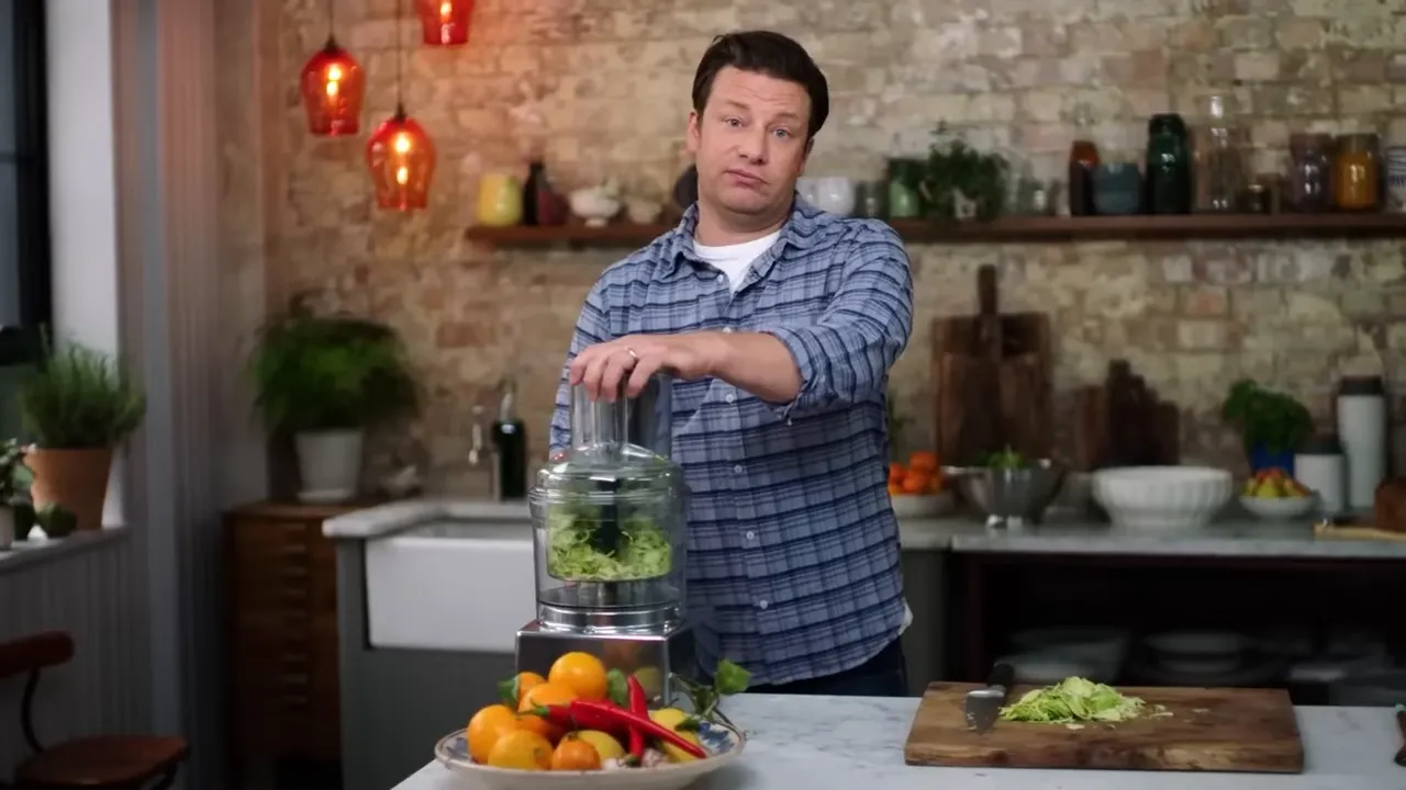 food processor shredding Brussels sprouts with a pile of shredded sprouts on a cutting board