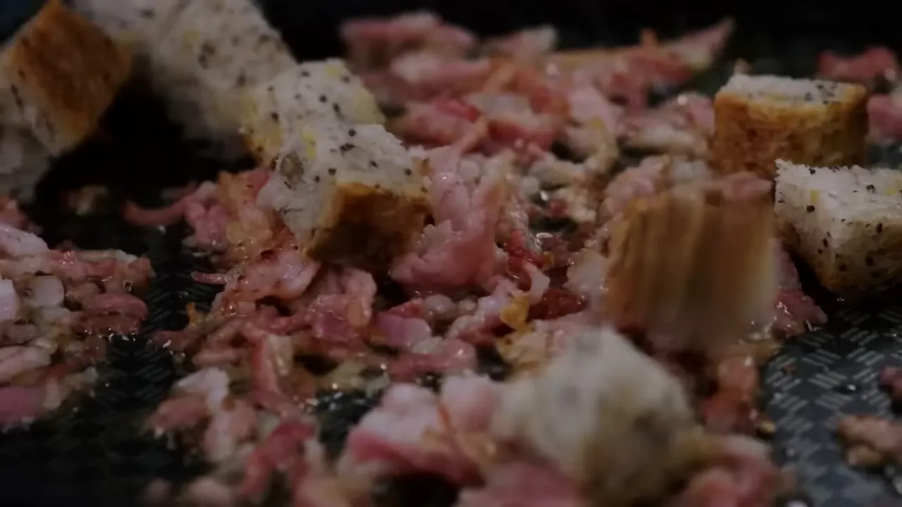 croutons and shredded bacon frying together in a pan