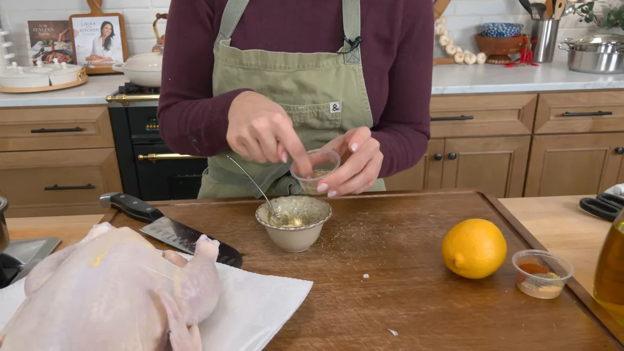 close-up of hands stirring dried herbs into softened butter on a cutting board with a raw chicken and lemon nearby