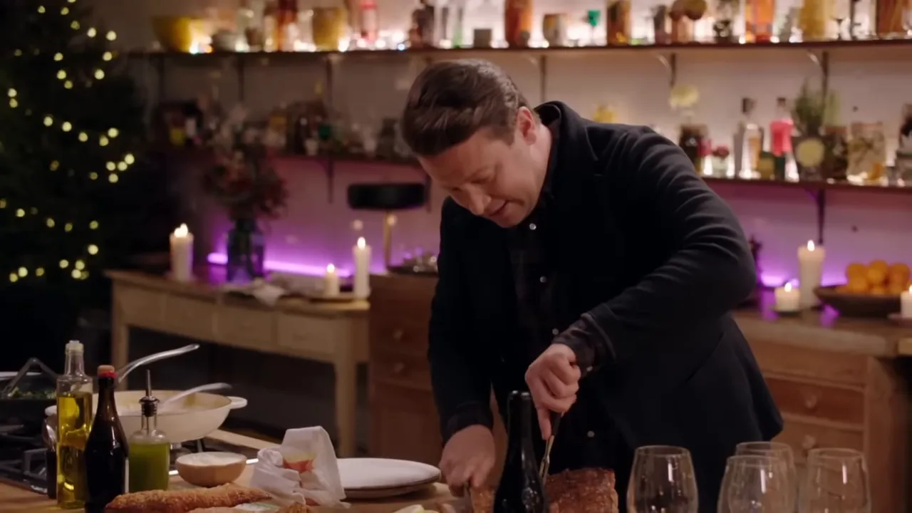 Chef carving a roasted pork loin with crispy crackling on a wooden board in a festive kitchen