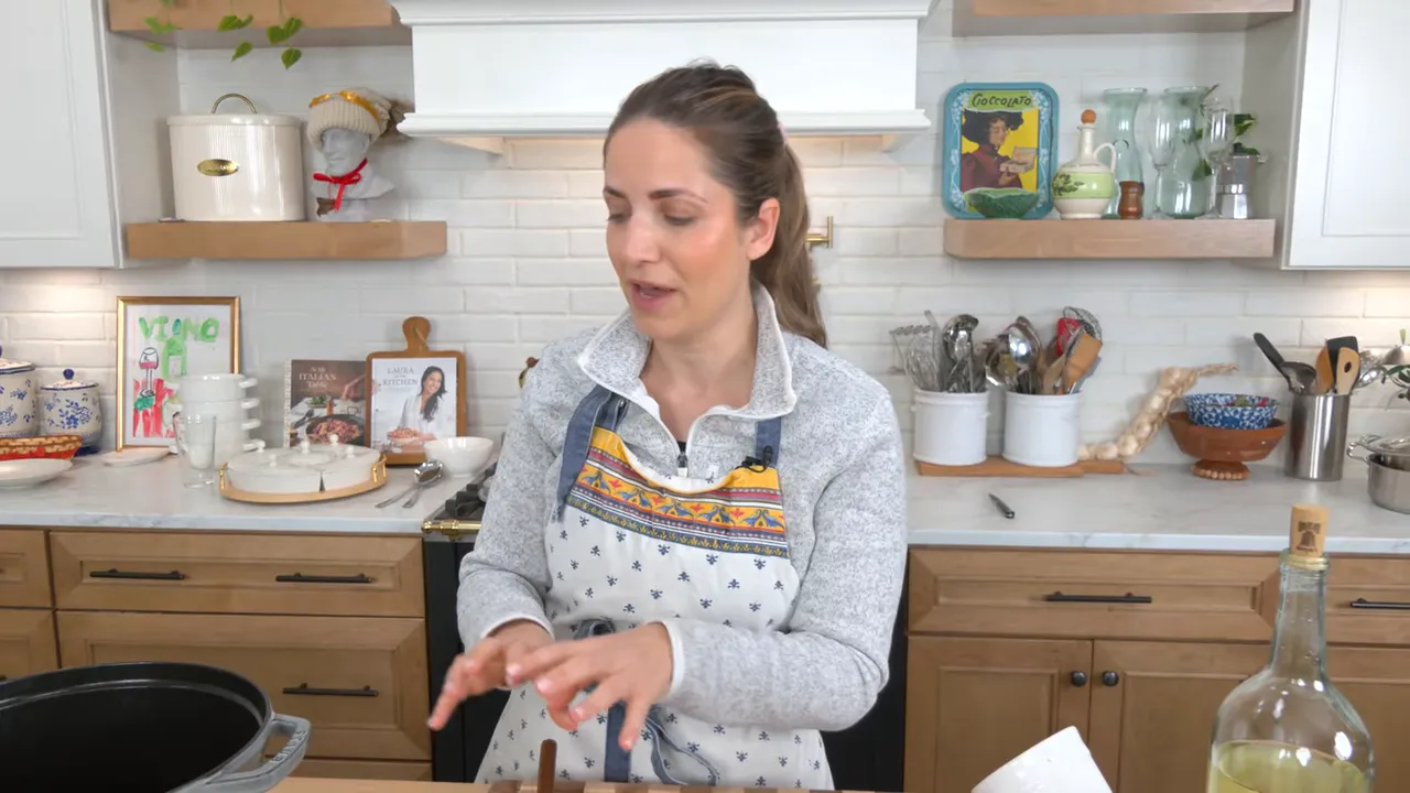 home cook in an apron speaking in a bright kitchen with a pot on the stove