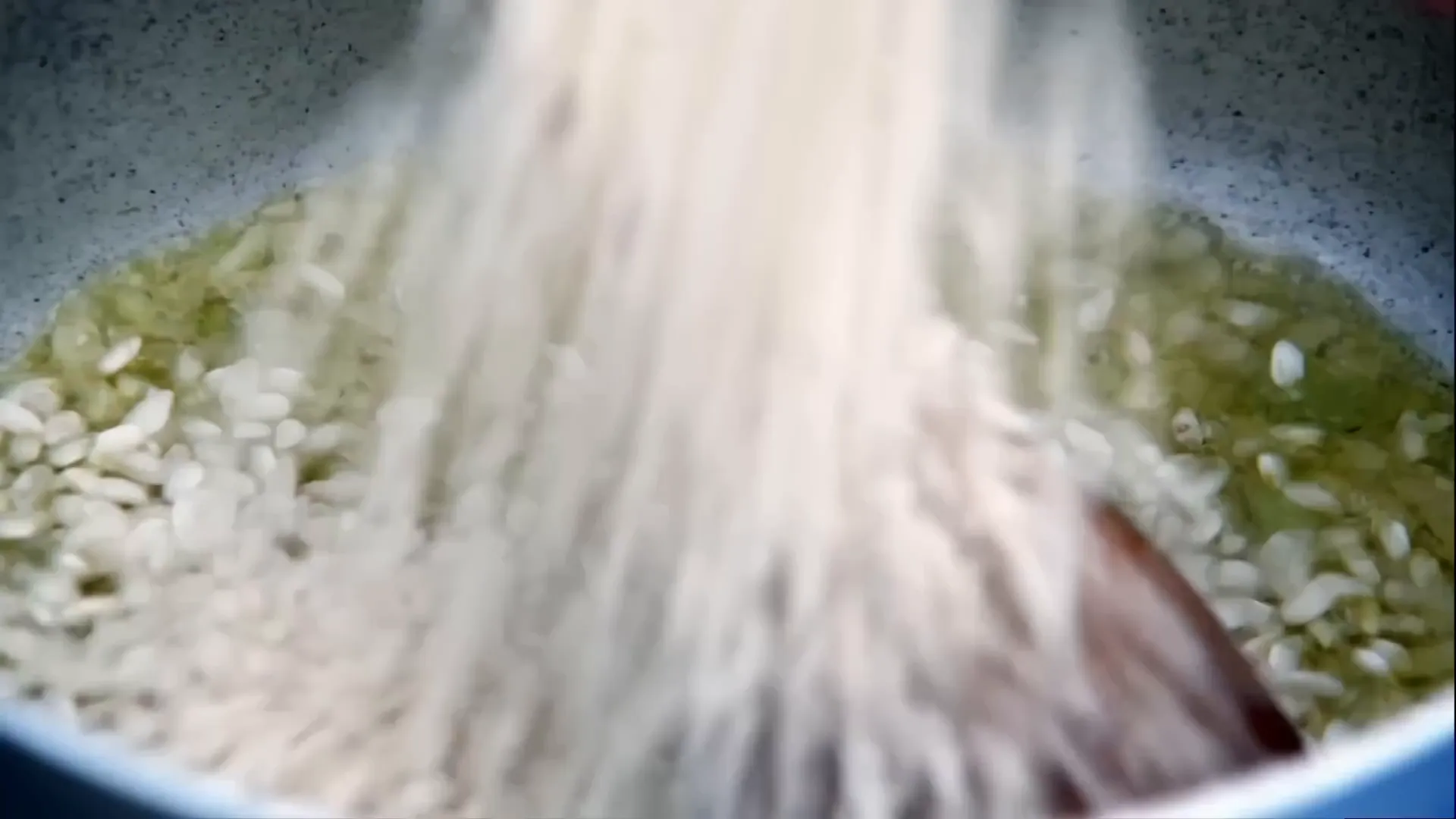 Generous handfuls of risotto rice added to the pan