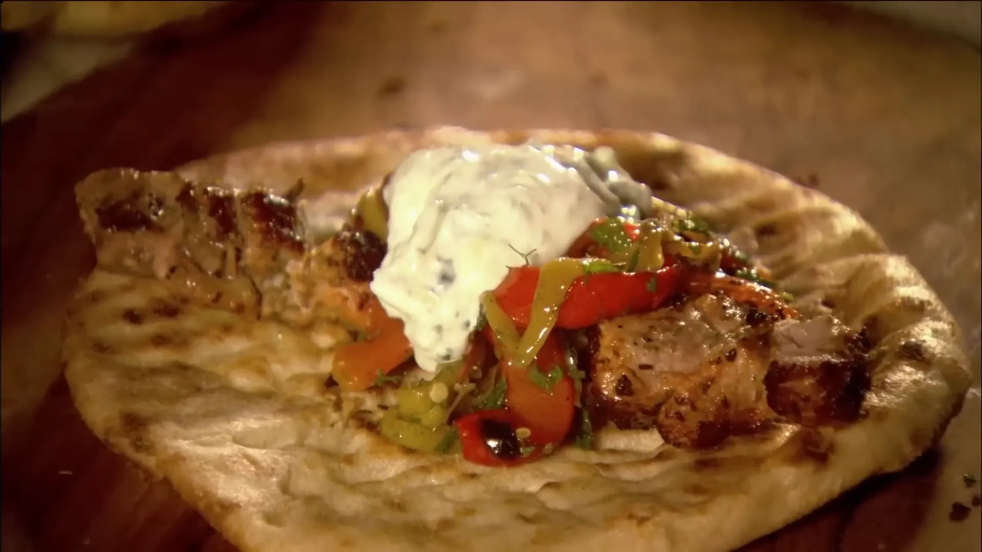 Finished pork kebab on flatbread with chili and tzatziki