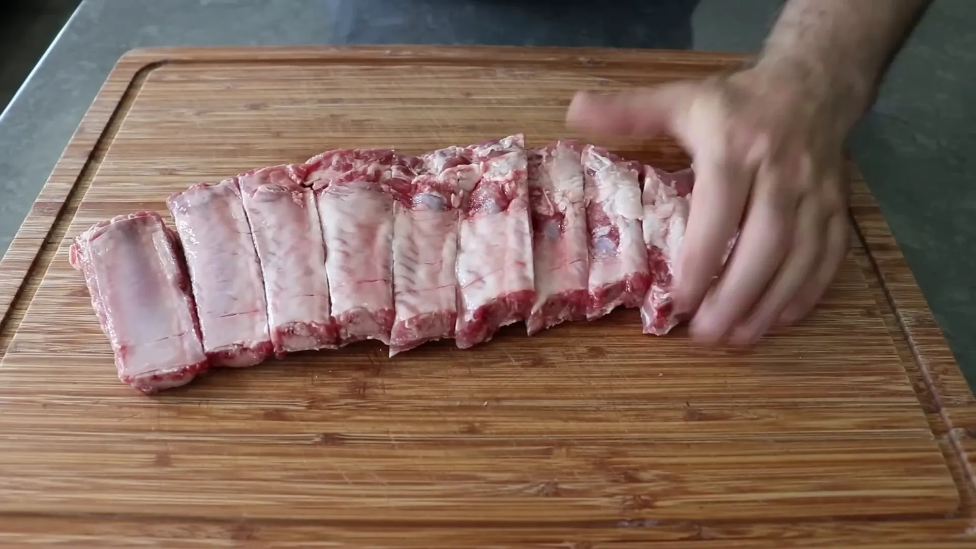 Cutting ribs between bones and seasoning with rub