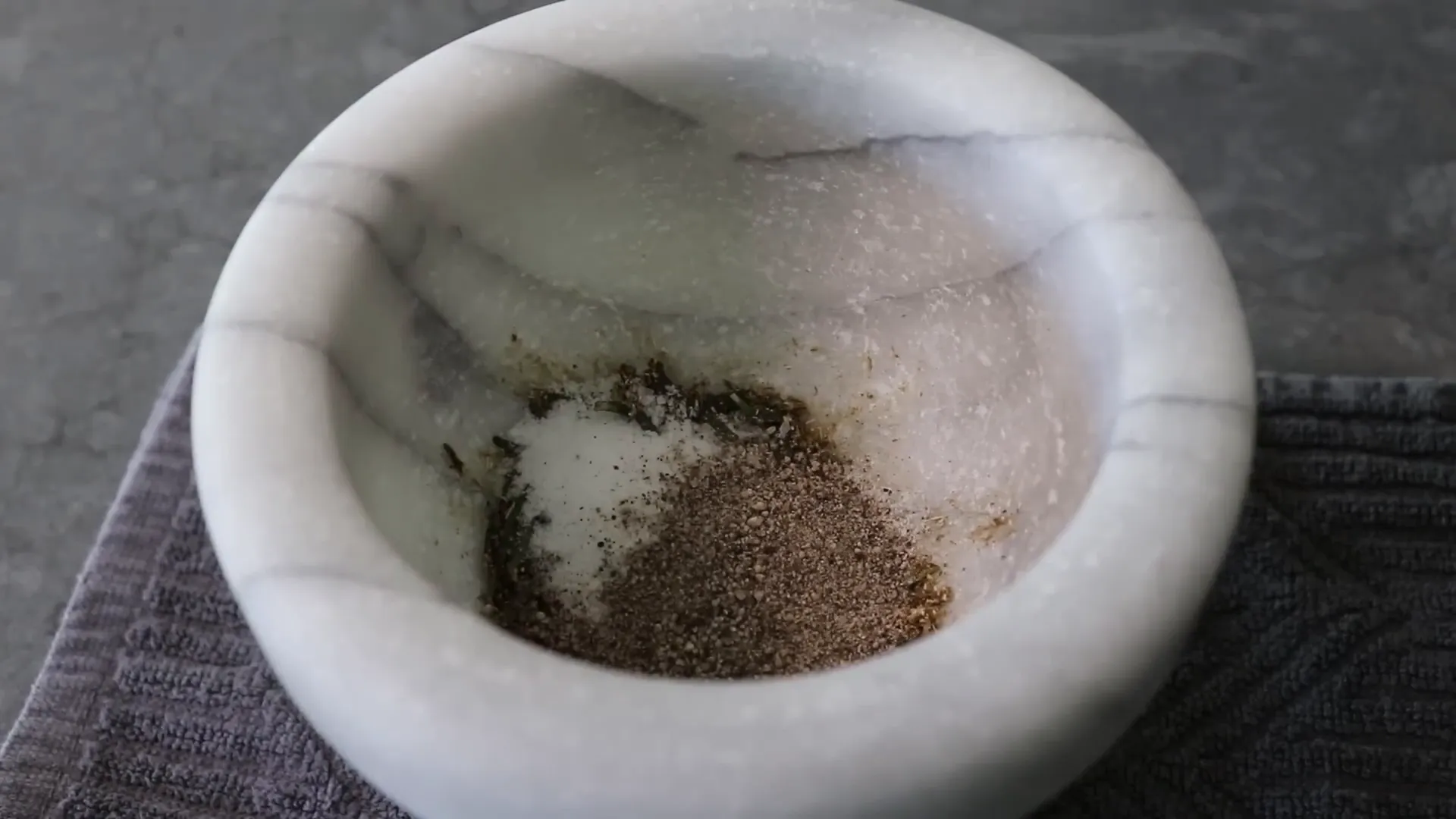 Grinding fennel seeds and bruising rosemary in a mortar