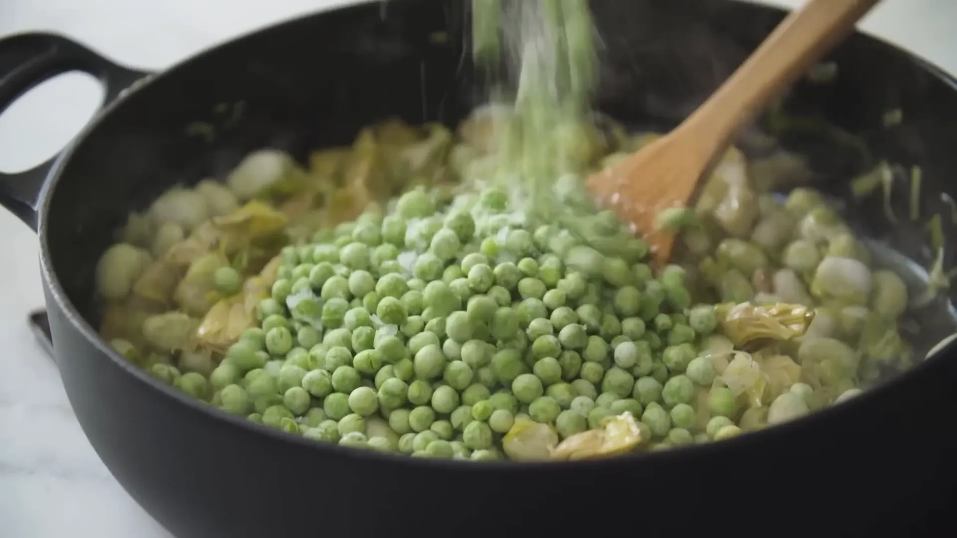 Adding frozen peas and broad beans to the cooking soup