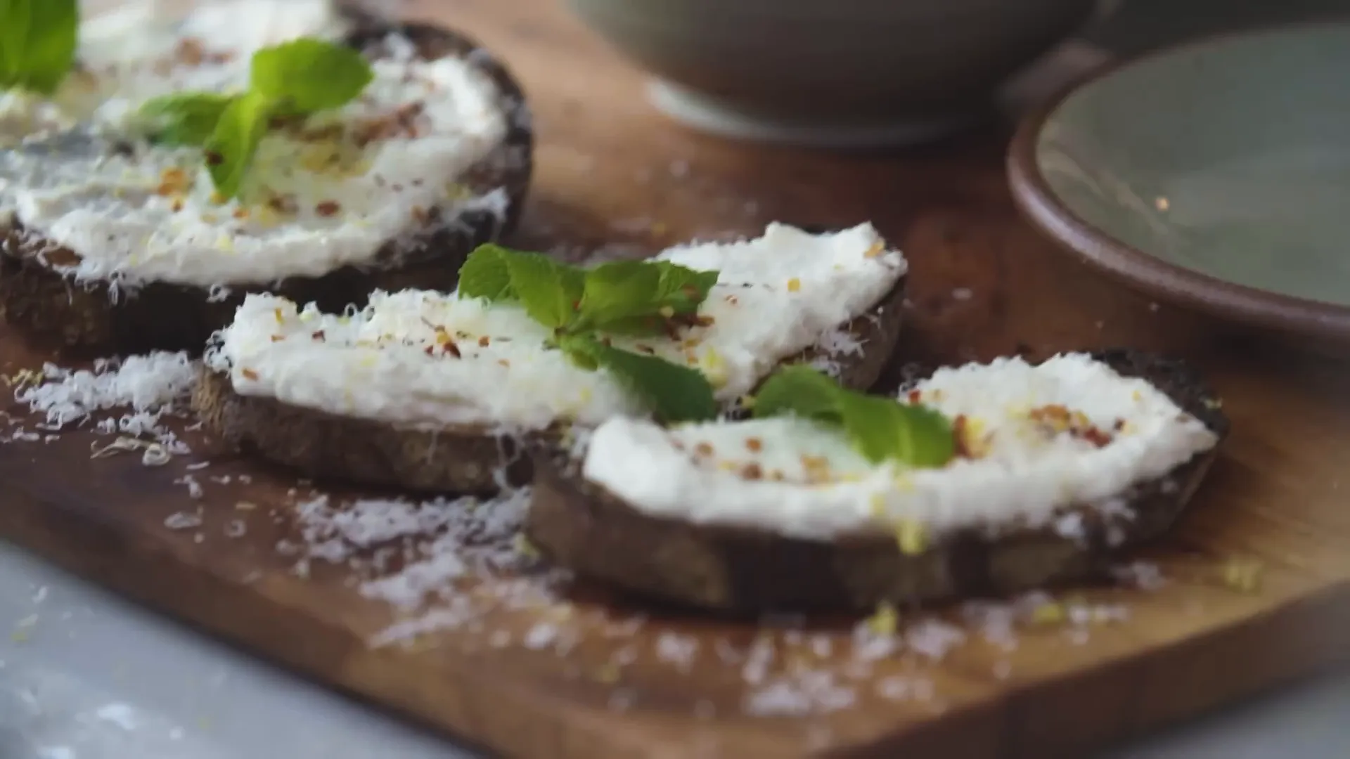 Ricotta toast garnished with lemon zest, parmesan, mint and chilli flakes