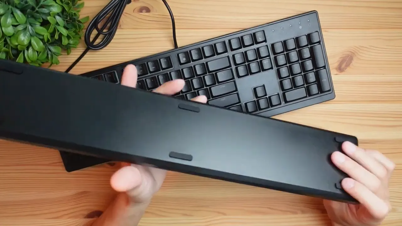 Detachable wrist rest underside showing rubber grip pads above a Razer keyboard on a wooden desk