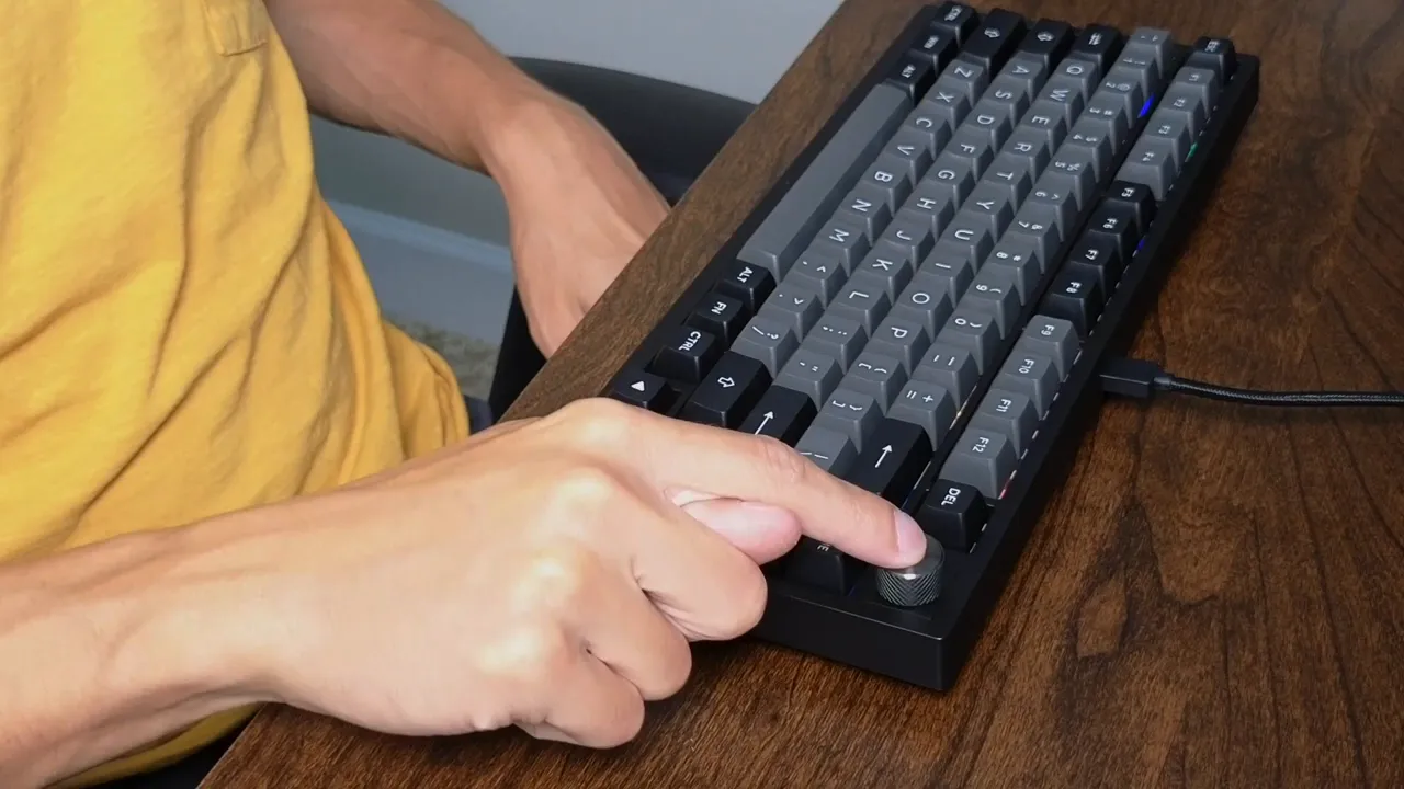Close-up of Epomaker TH80 SE 75% keyboard with a hand pressing the metal volume knob on the top-right corner.