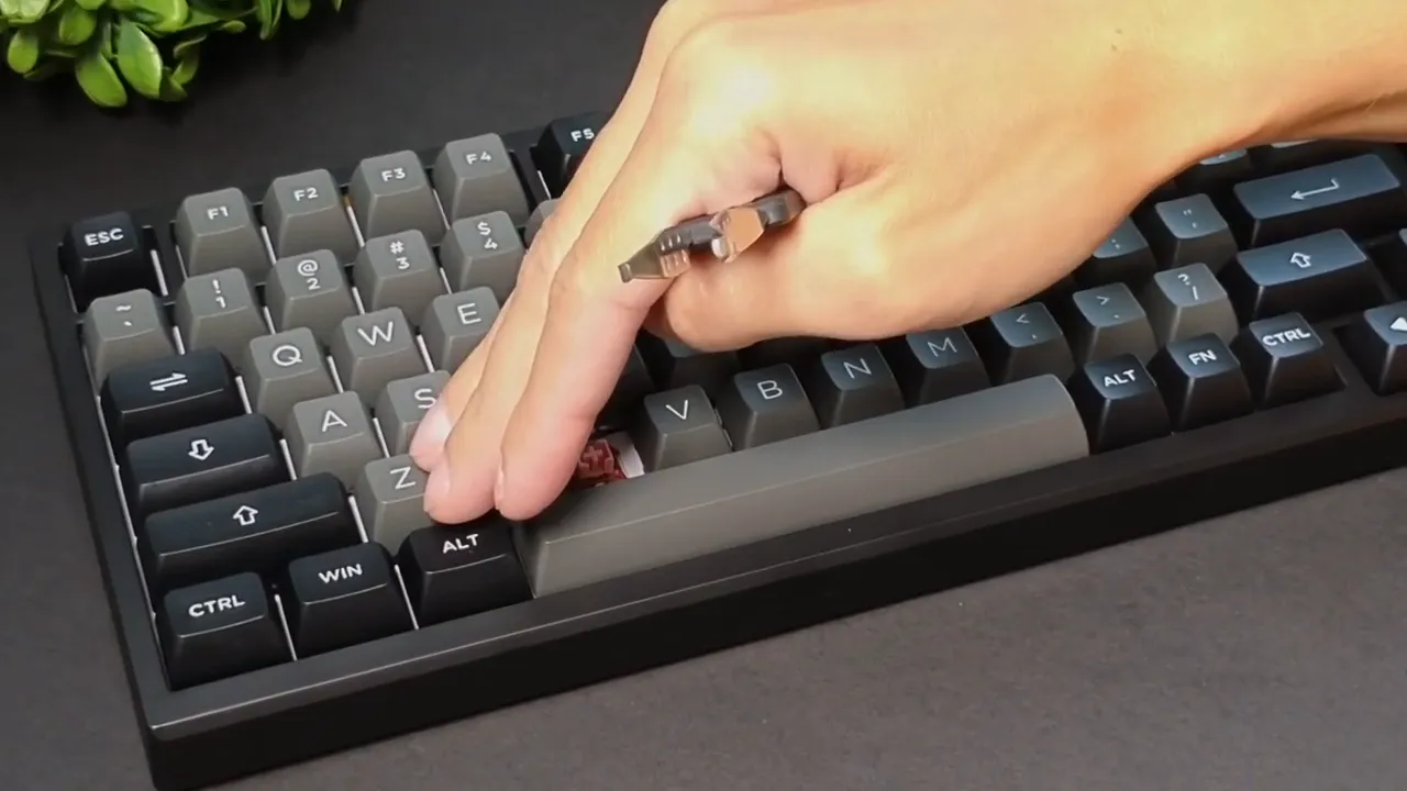 Hand using a keycap puller to remove a keycap from the Epomaker TH80 SE, revealing a pink Flamingo linear switch