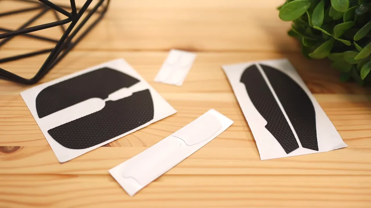 Several black grip stickers and white backing strips laid out on a wooden desk