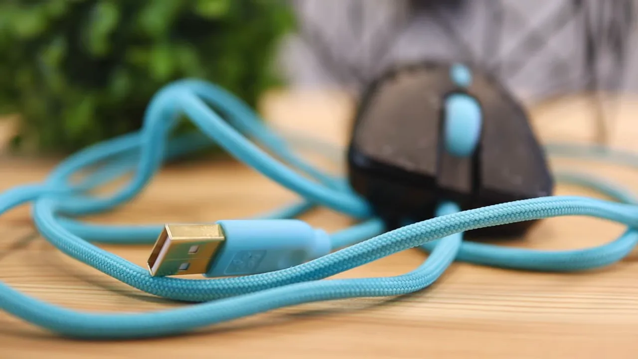 Blue mouse cable coiled on the desk with the mouse blurred in the background