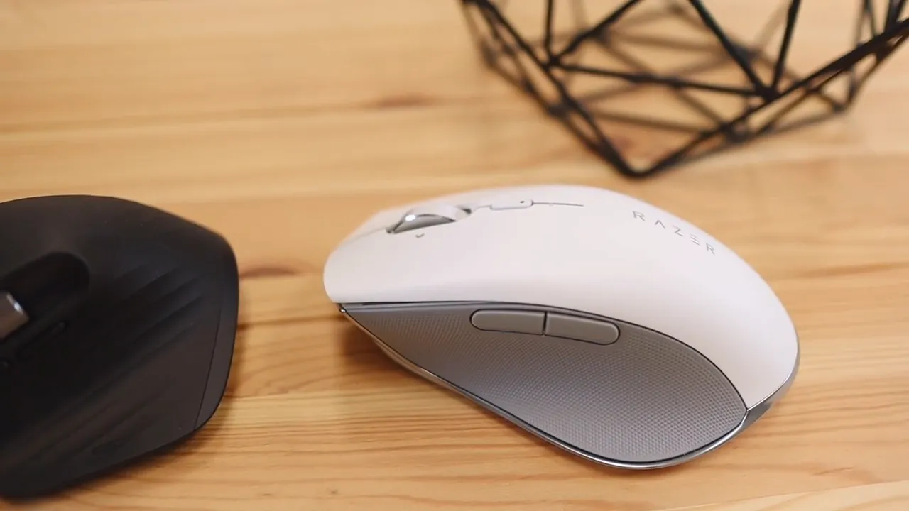 Black Logitech MX Master 3 beside white Razer Pro Click on a wooden desk