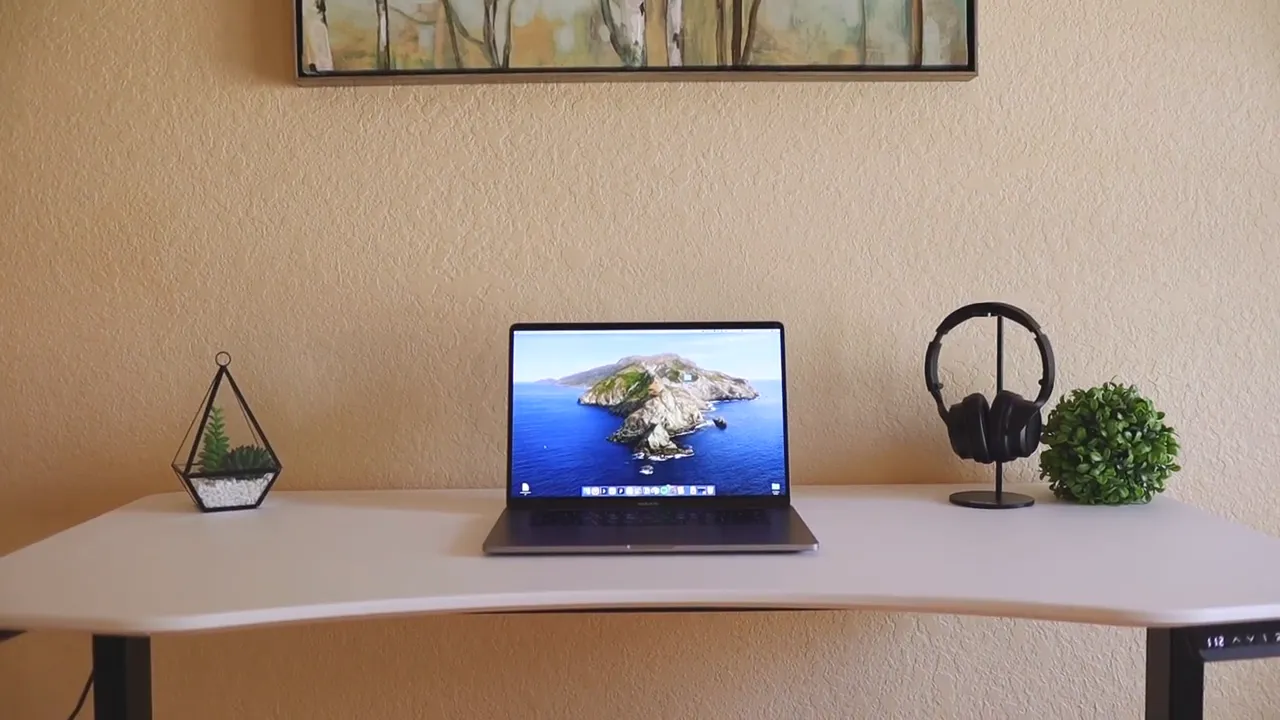 Centered view of ElementDesk showing curved front edge, laptop, headphone stand and plant