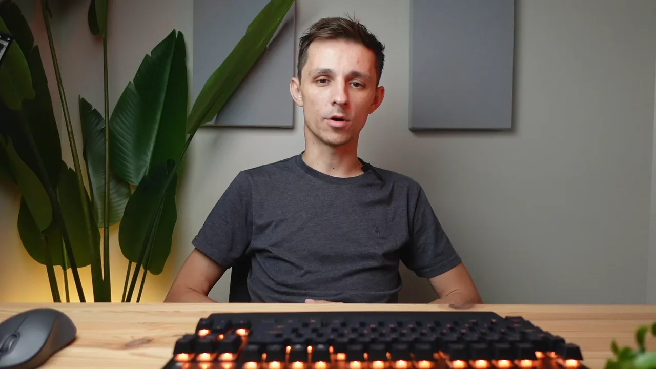 Presenter behind a desk with a SteelSeries Apex Pro TKL keyboard lit orange in the foreground