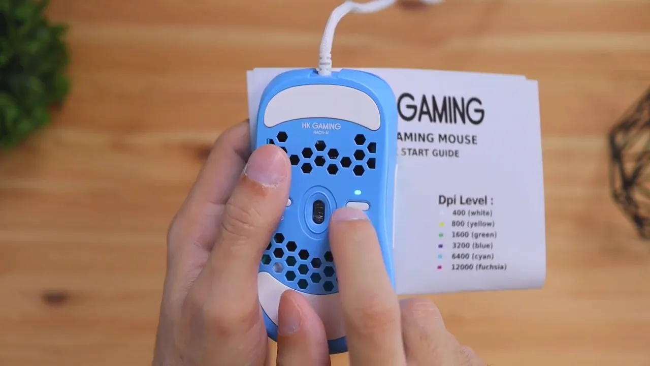 Bottom of the blue mouse held in hands with quick start guide showing DPI level list