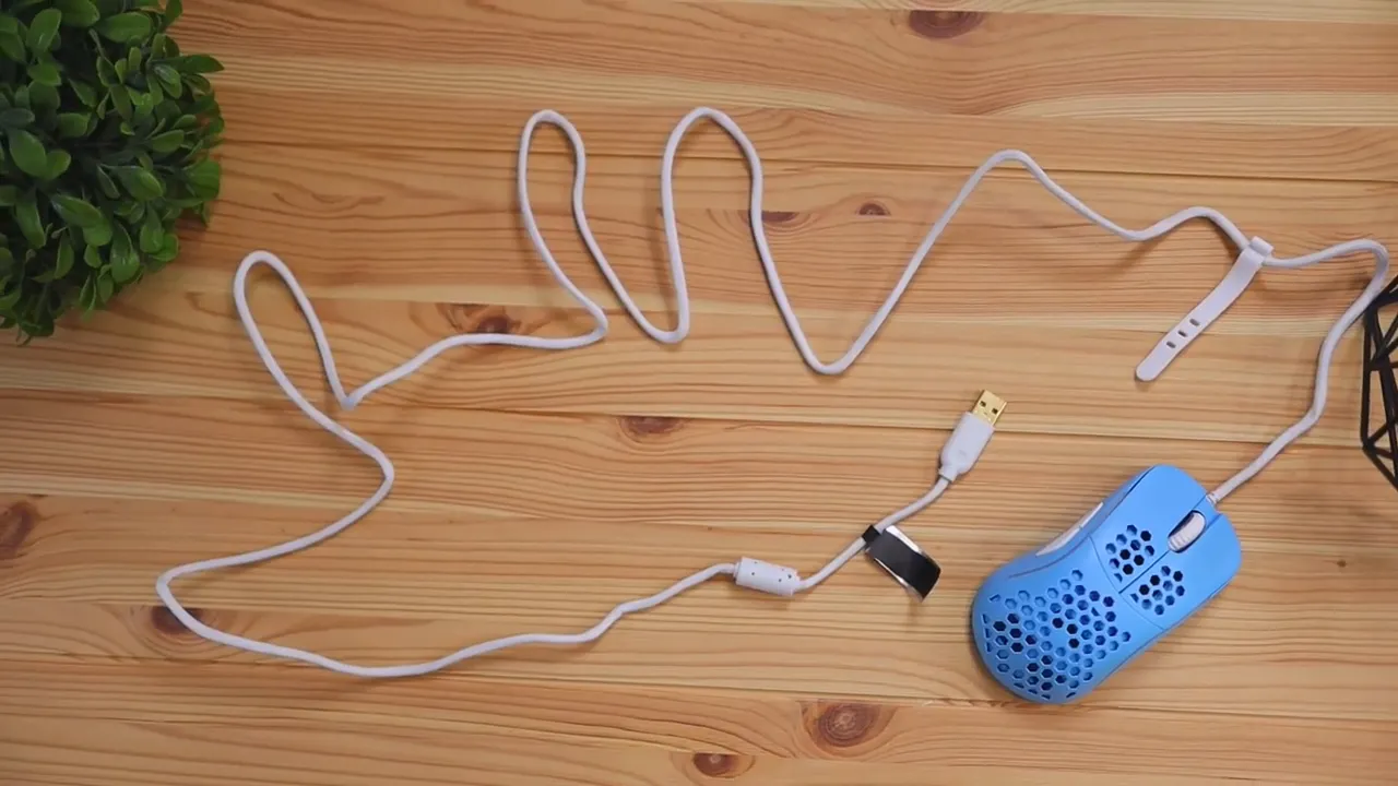Blue mouse and long white cable spread across a wooden desk