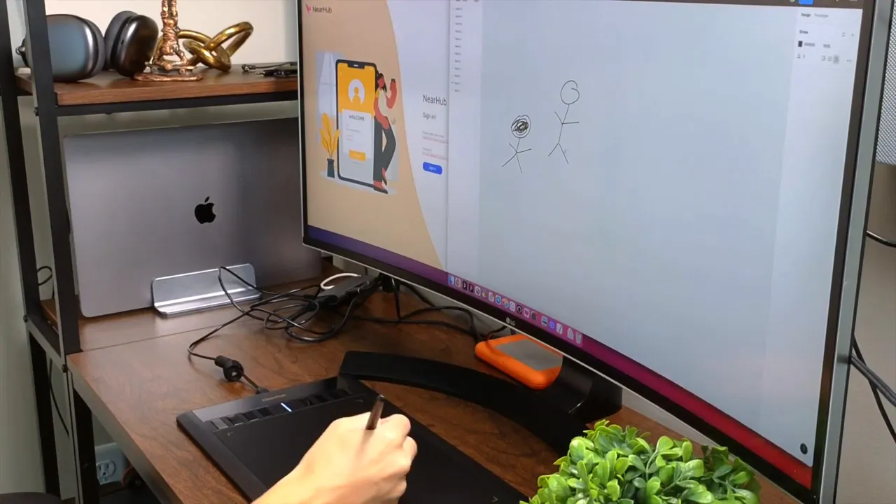 NEARHUB S13 drawing tablet in use with stylus drawing stick figures on the NearHub web canvas displayed on a monitor