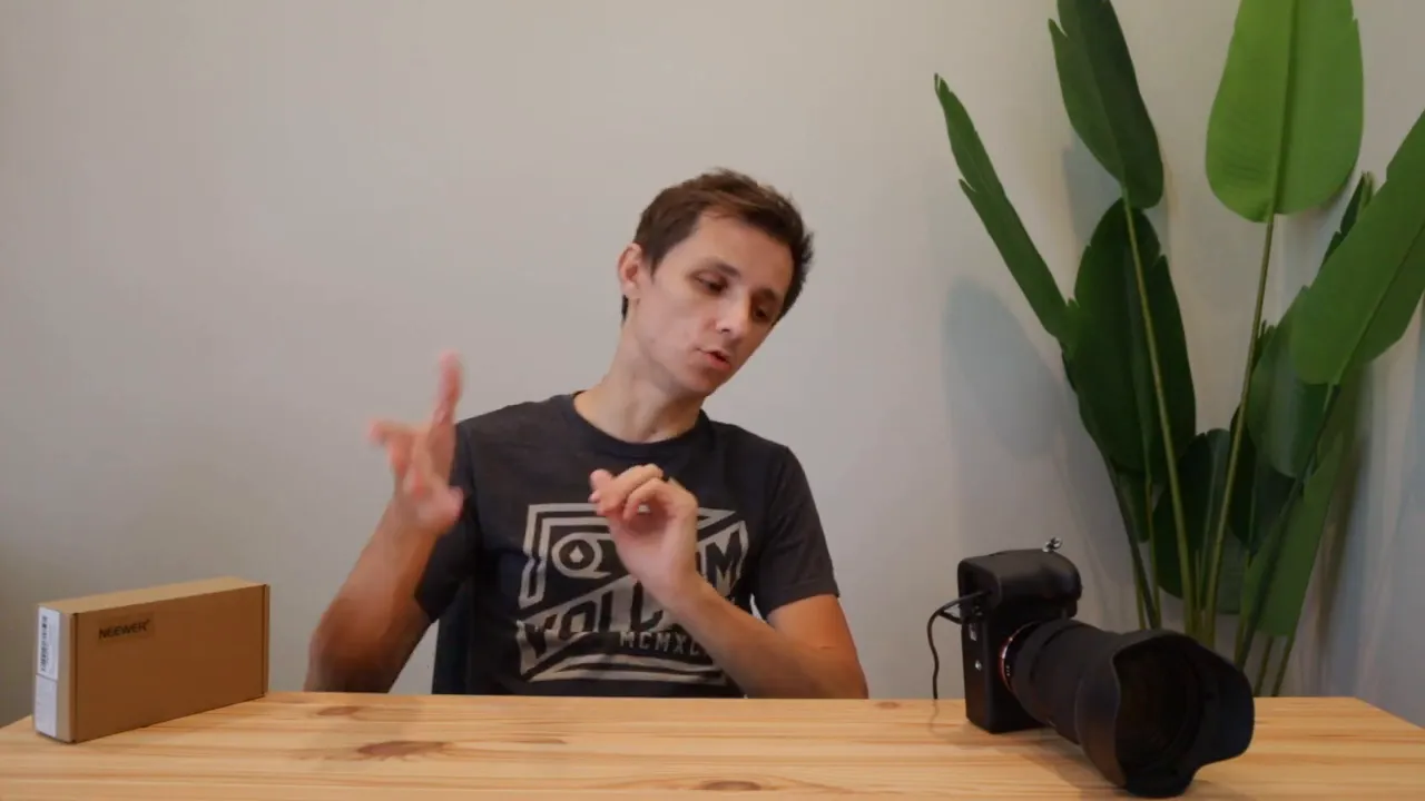 Desk setup showing a camera with a long lens on the right, a Neewer box on the left, and a power brick connected to the camera