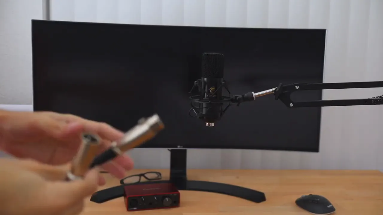 Hands plugging an XLR cable into the Tonor TC20 condenser microphone on a boom arm