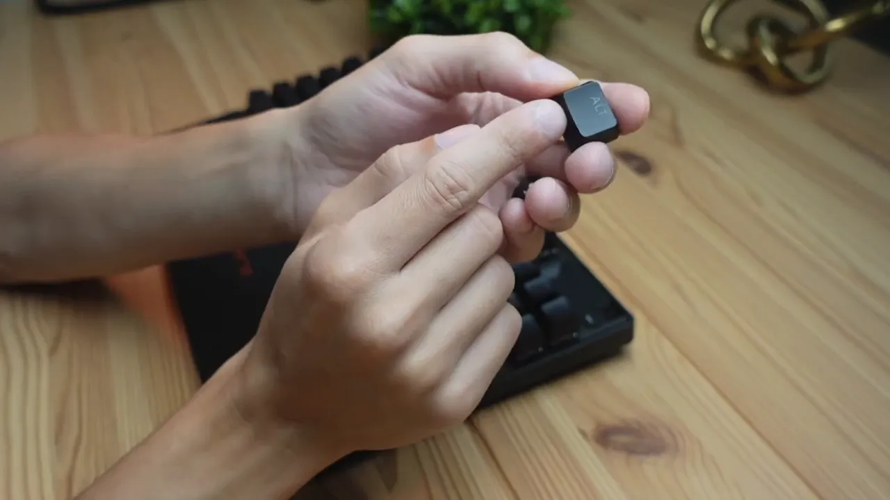 Hands holding the 'Alt' keycap showing the textured, concave surface from a SteelSeries Apex Pro TKL