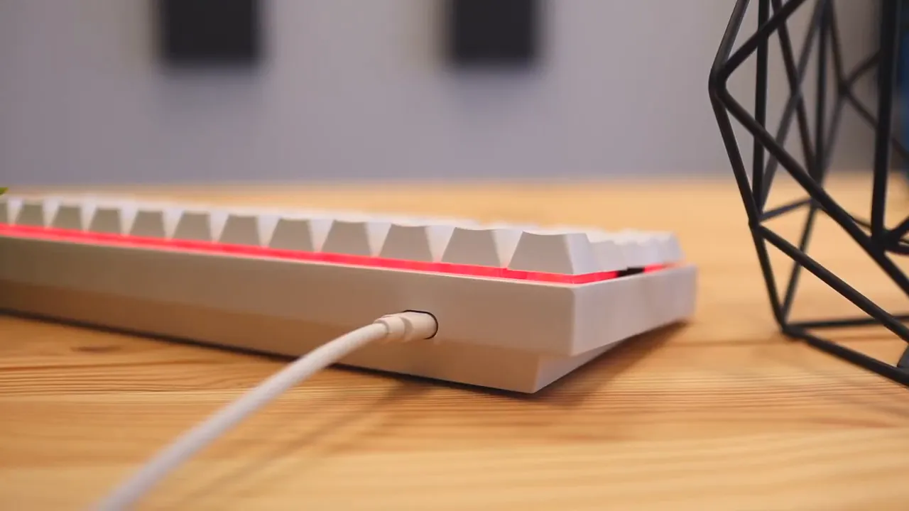 Side view of the white keyboard with a red light strip and cable connected