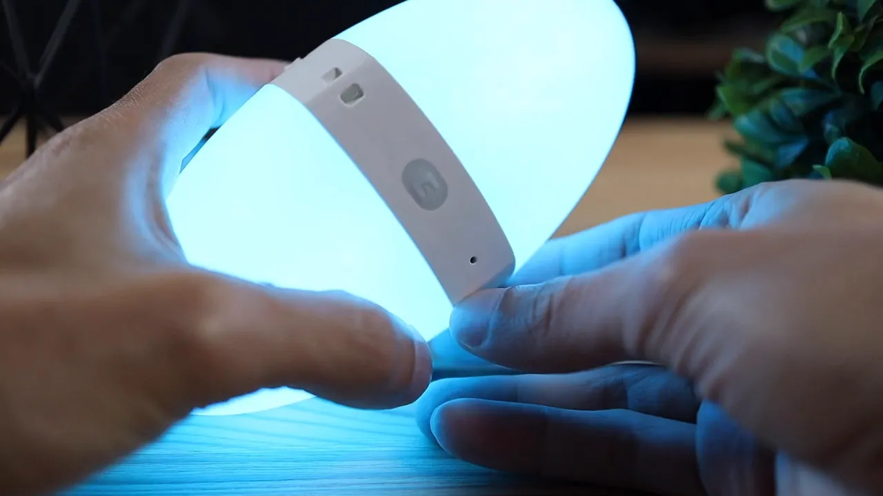 Close-up of hands holding the Ecolor Egg lamp showing the control band and button