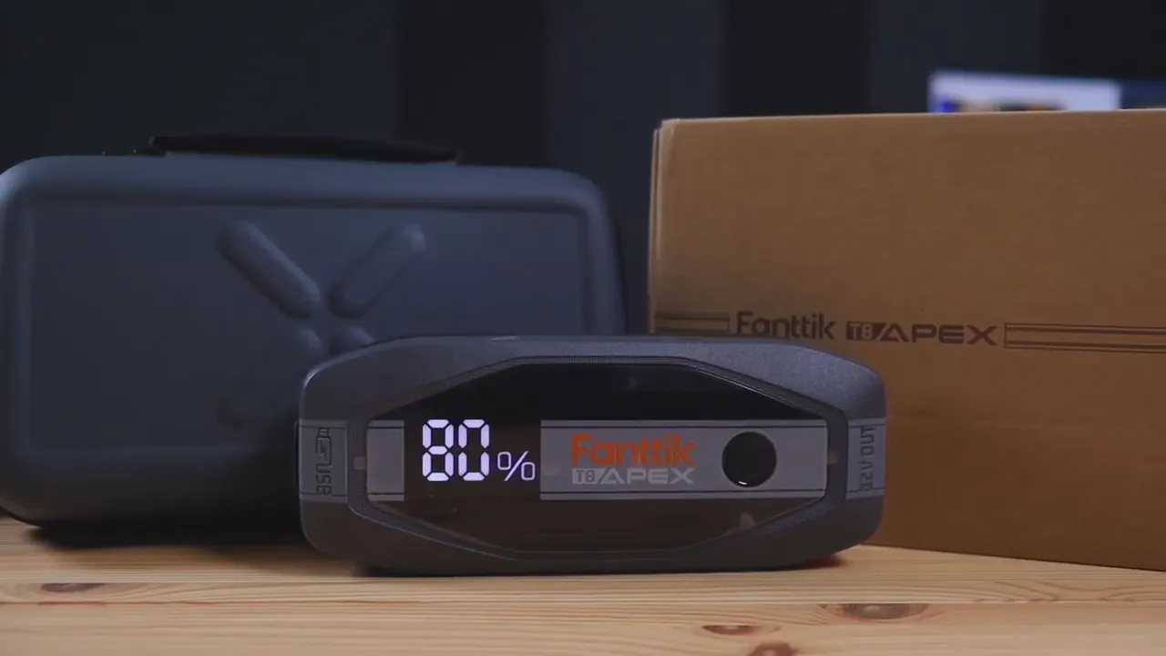 Front view of FANTTIK T8 APEX jump starter with 80% battery display, carrying case and product box in background
