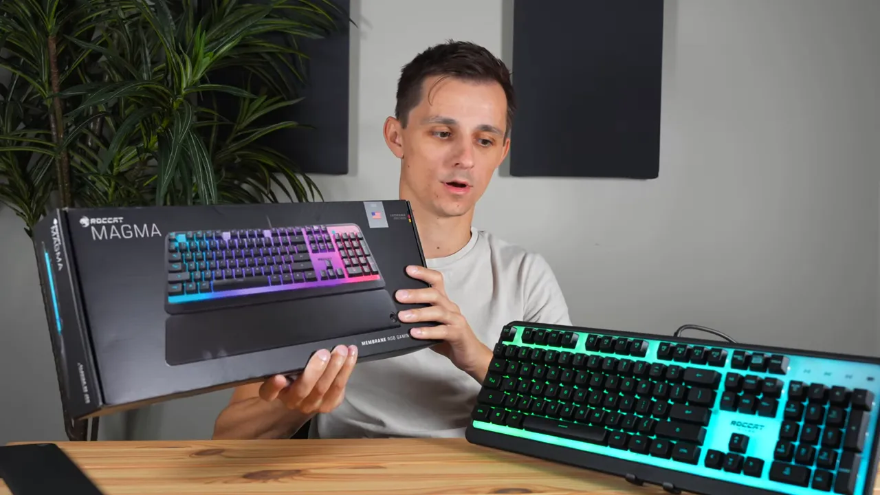 Reviewer holding ROCCAT Magma retail box alongside the full-size Magma keyboard with RGB lighting