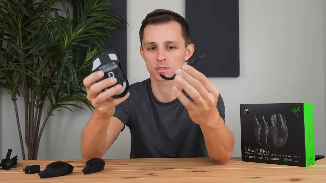 Presenter holding a removed magnetic side plate next to the Razer Naga V2 Pro to demonstrate removal