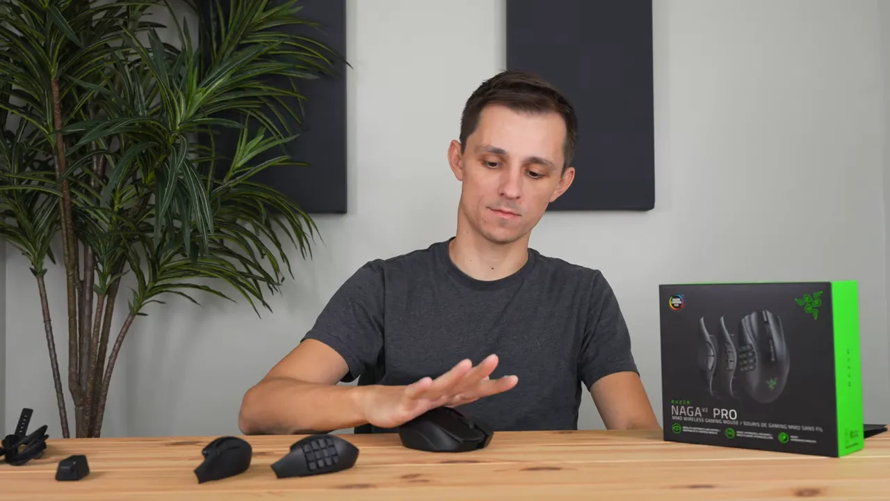 Hand demonstrating a palm grip on the Razer Naga V2 Pro with detachable side plates visible on the table