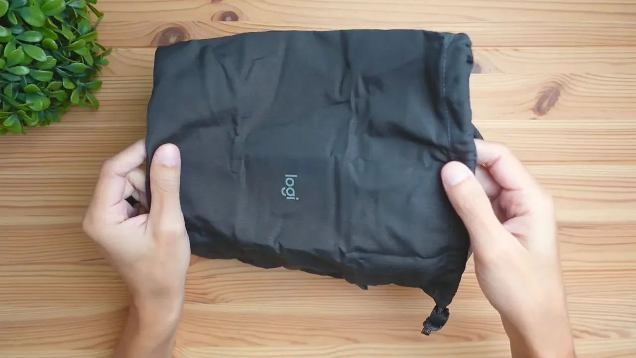 Fabric drawstring bag and charging cable laid out next to headset