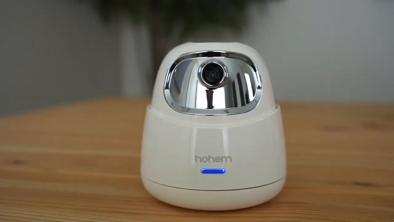 Close-up of the Hohem GO two-axis mount on a wooden table showing the chrome camera housing and blue status LED.