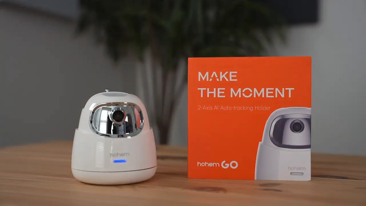 Hohem GO unit next to its orange box on a wooden table with a blue LED indicator illuminated