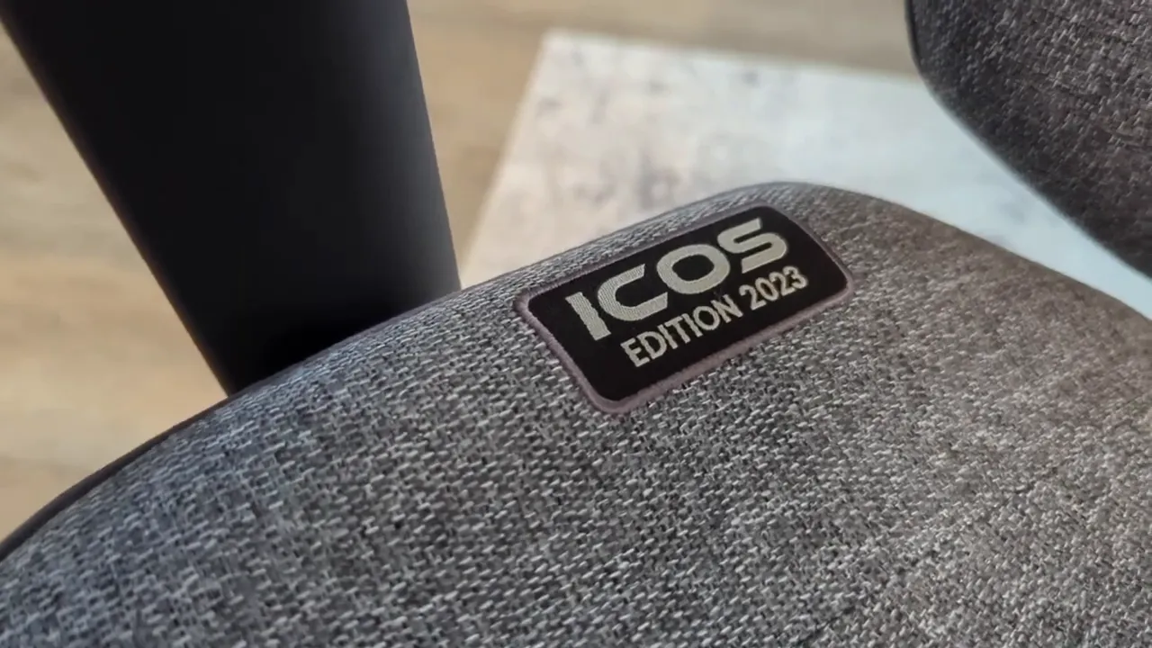 Quersus ICOS 2023 logo patch on gray fabric seat close-up showing weave and stitching