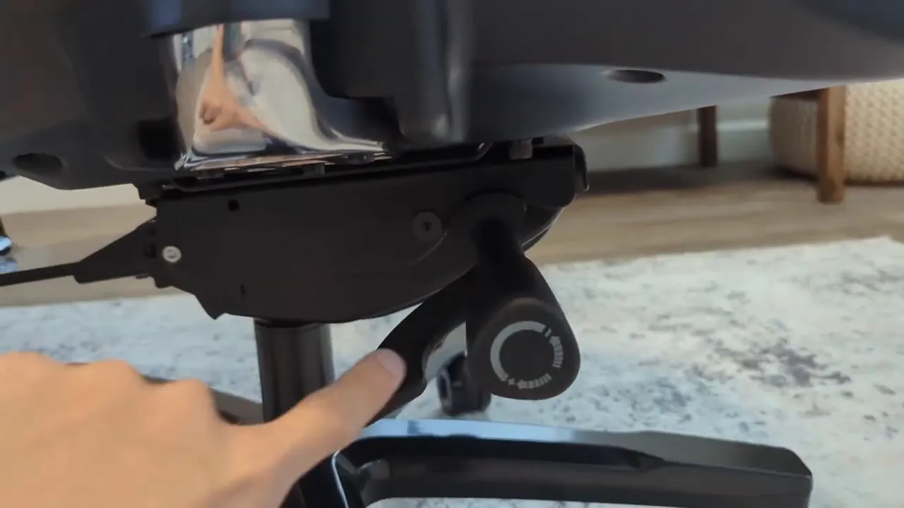 Close-up of the Quersus ICOS tilt lever and tension adjustment knob under the seat with a finger indicating the control