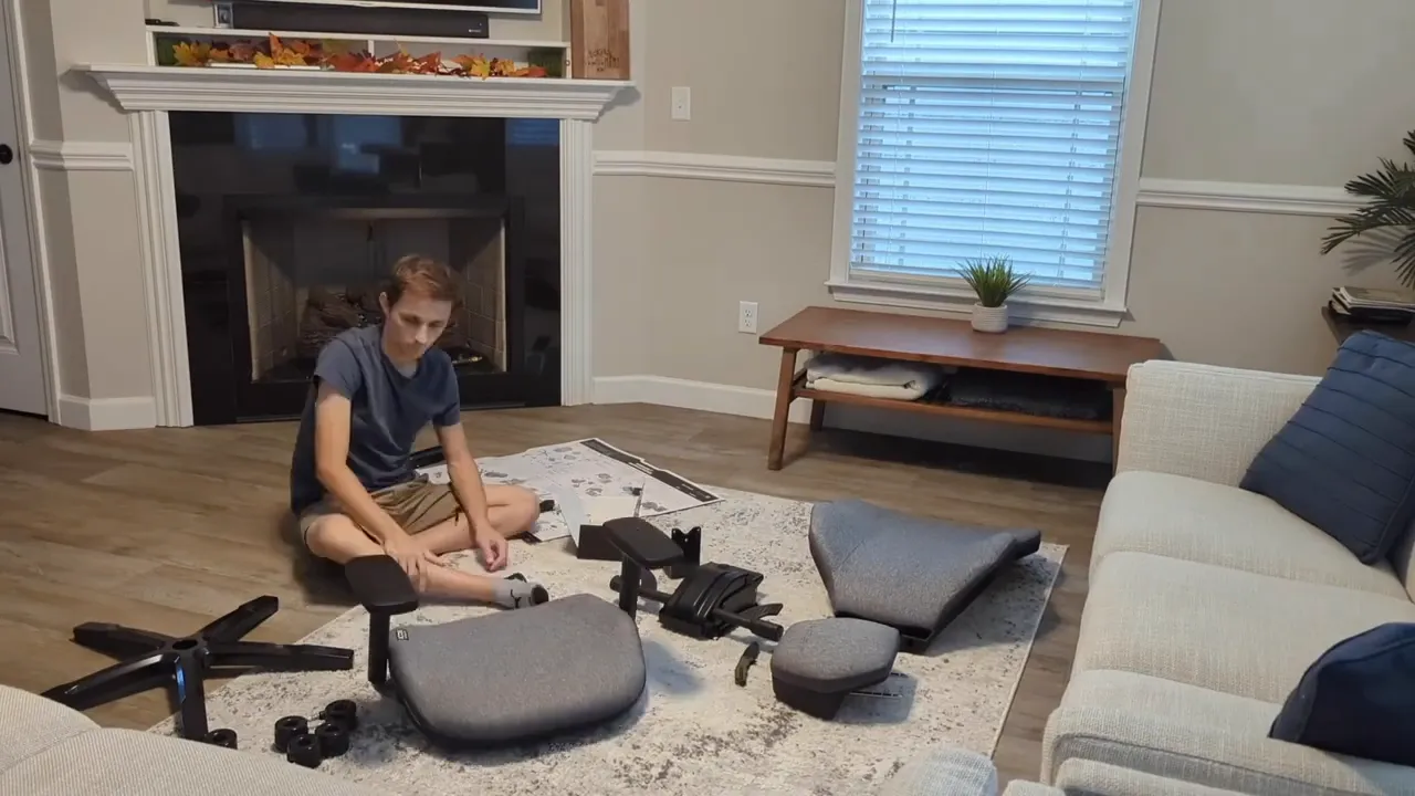Person assembling the Quersus ICOS chair with parts laid out on the floor in a living room