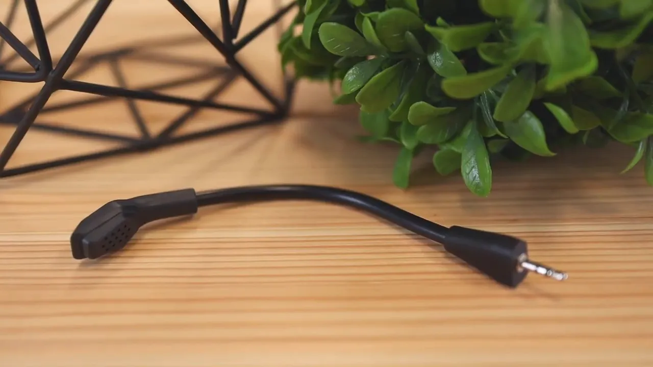 Detachable boom microphone lying on a wooden desk near green leaves