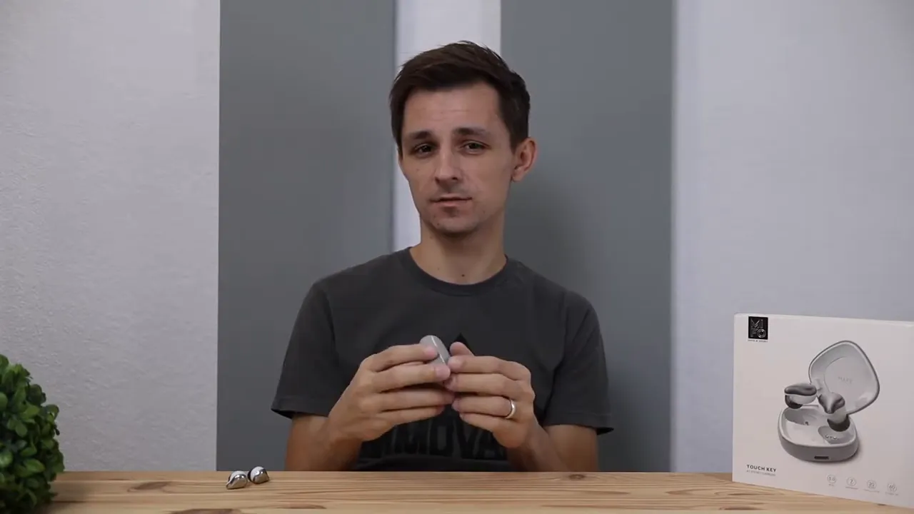 Open charging case with two earbuds inside and a finger near the lid hinge