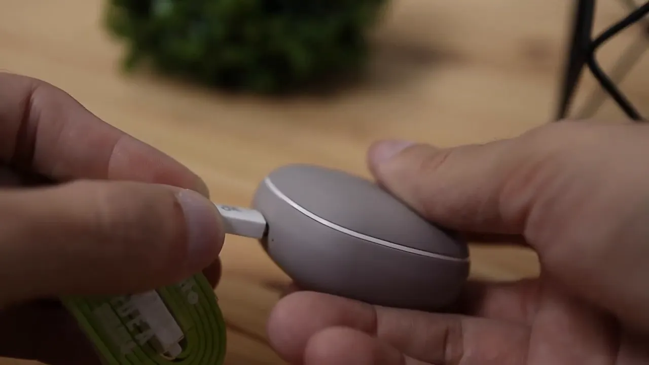 USB-C cable being plugged into the side of the gray charging case