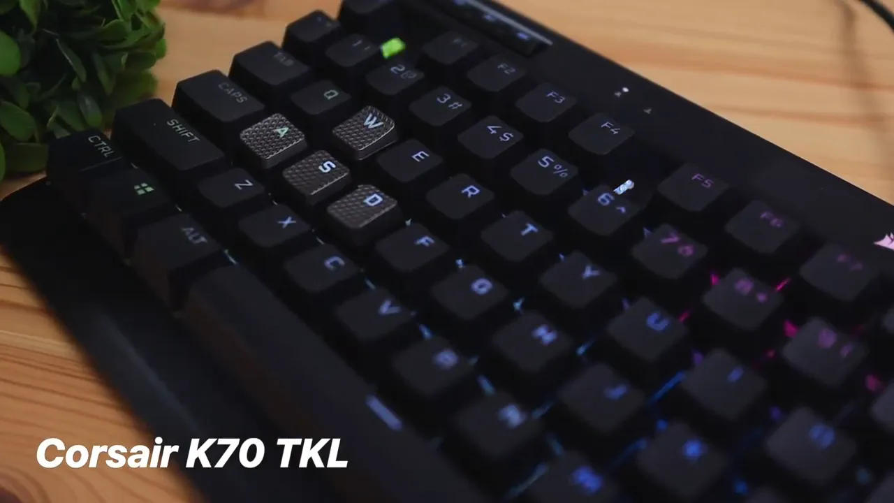 Corsair K70 TKL close-up showing textured WASD keycaps and per-key RGB lighting on a wooden desk