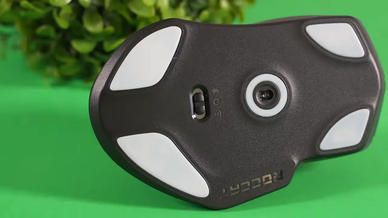 Full underside of Roccat Kone Air showing all five white glider pads and optical sensor on green background