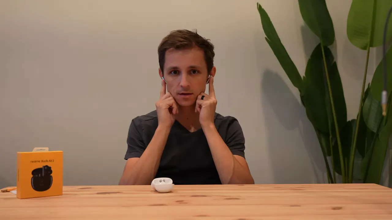 Reviewer pressing both Realme Buds Air 2 earbuds at the touch area to toggle ANC