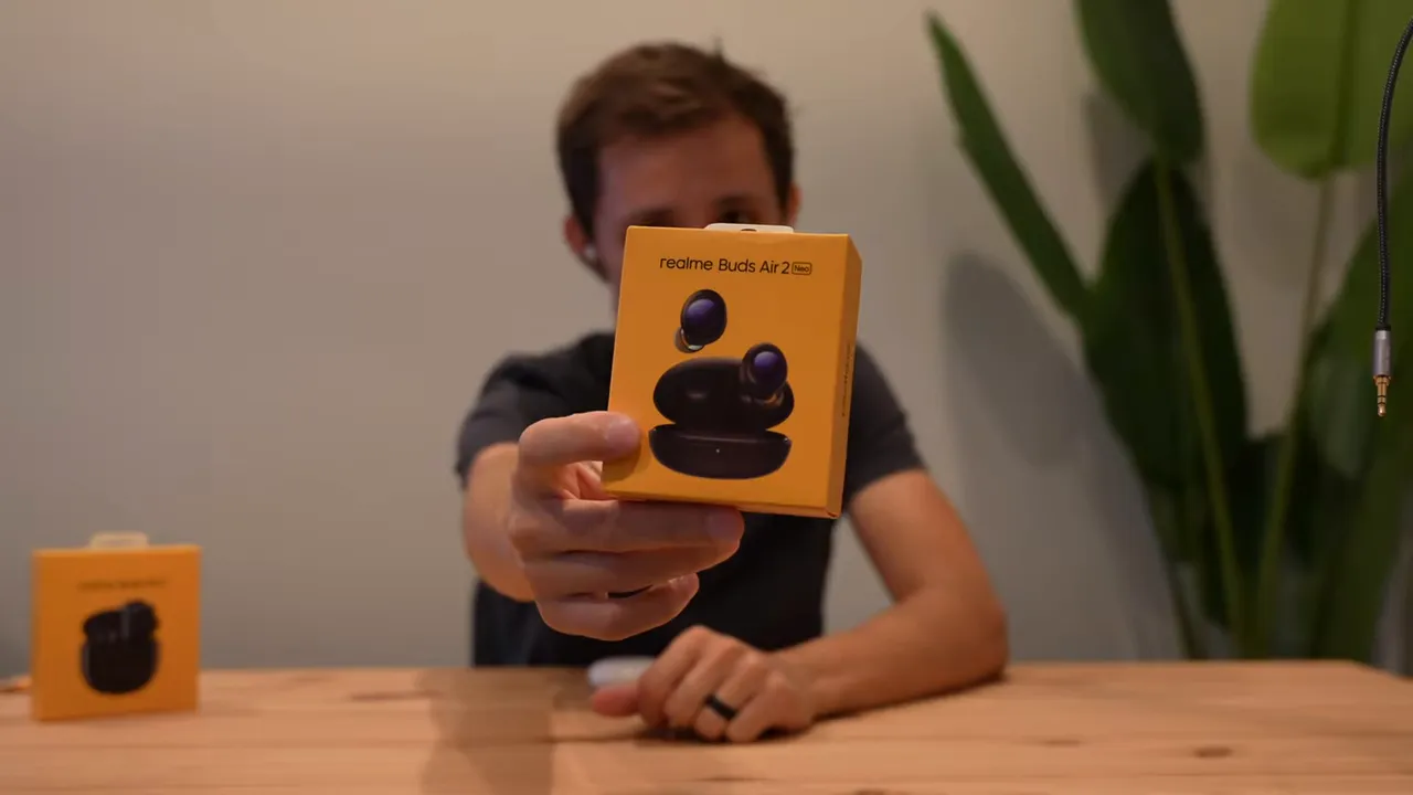 Front-facing close-up of the Realme Buds Air 2 Neo orange retail box being presented to the viewer.