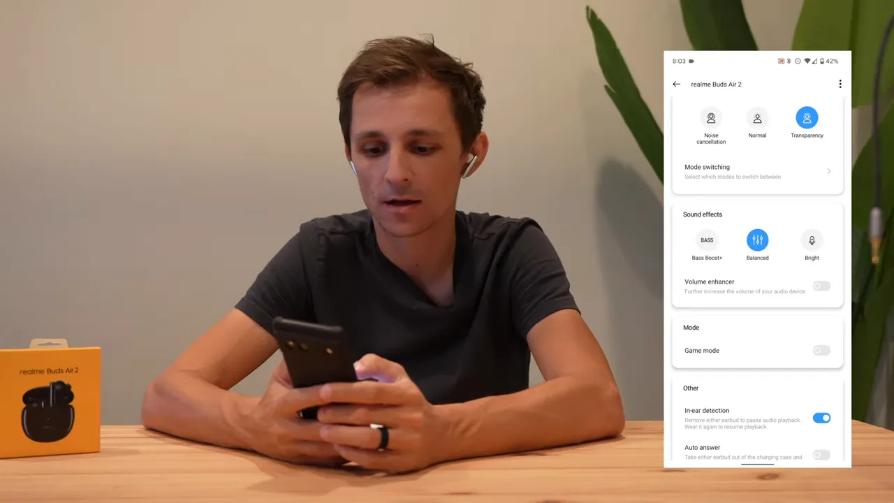 Clear screenshot of Realme Link settings showing Noise Cancellation, Transparency, EQ presets and in-ear detection overlaid on a reviewer holding a phone.