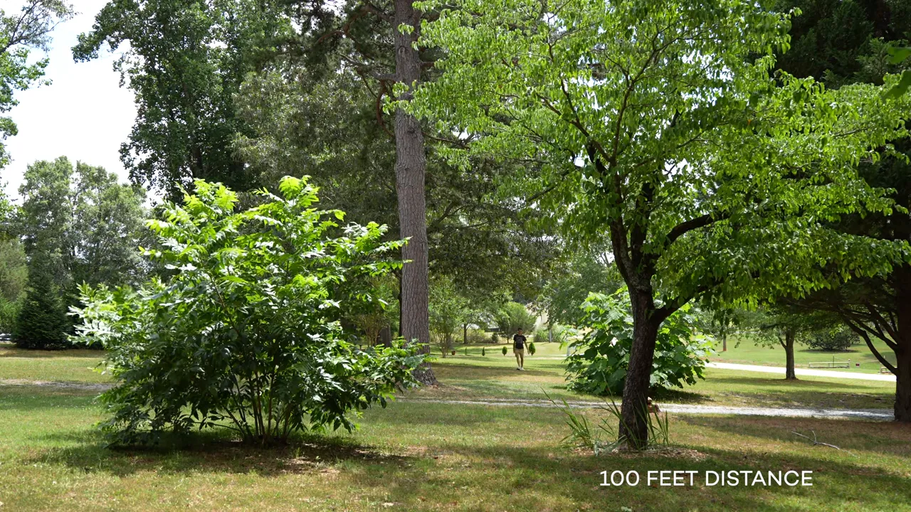 Wide outdoor shot showing the presenter at about 100 feet distance with '100 FEET DISTANCE' text overlay